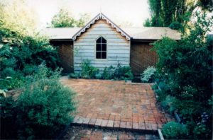 A garden shed with sliding lattice screens over shelving either side.