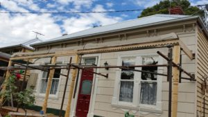 An original verandah under restoration; new posts,frieze, subfloor, deck and gutter / roof.